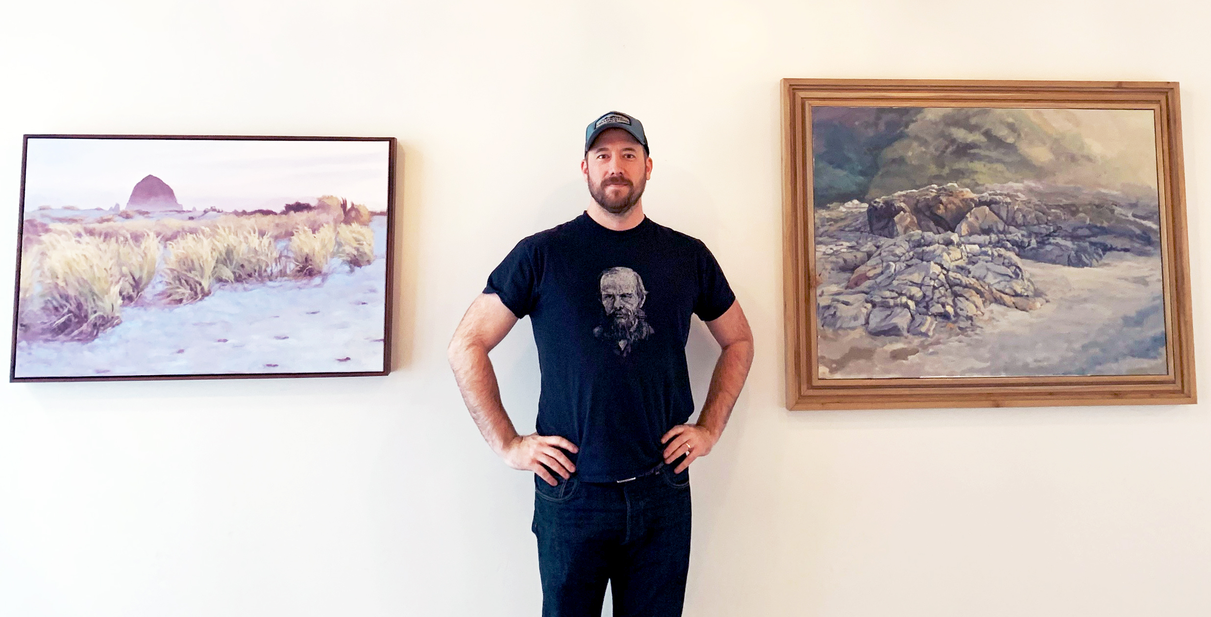 Adam Kenney standing next to his paintings