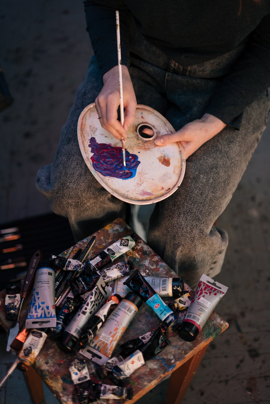 a painter mixing paint on palette using a paintbrush